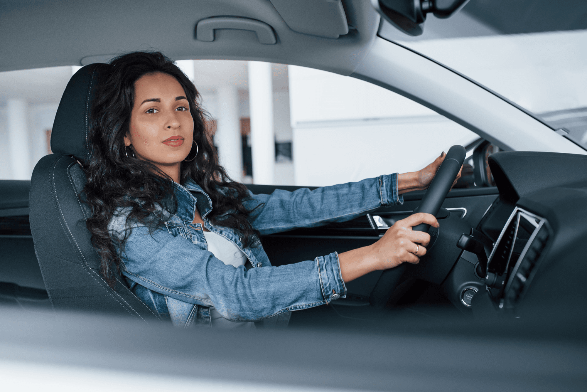 Hands on the steering wheel of a car interior in daylight